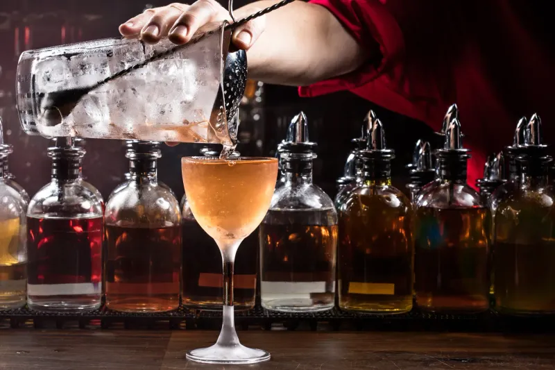 Bartender double straining a stirred cocktail into a Nick and Nora glass at the Dead Rabbit