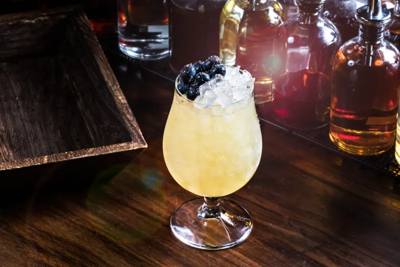 Kissin Cousin cocktail topped with blueberries and crushed ice in a stemmed glass, Dead Rabbit bar