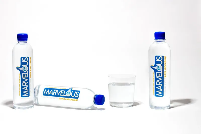 Marvelous alkaline water bottles and a poured glass on a white background, beverage packshot