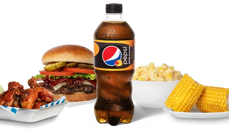 Pepsi Zero Sugar Mango bottle with wings, a bacon burger, mac and cheese, and corn, concession menu photograph