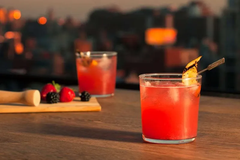 Berry fizz cocktail with the New York City skyline behind