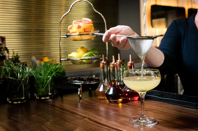 Bartender double straining a cocktail, action drinks photography